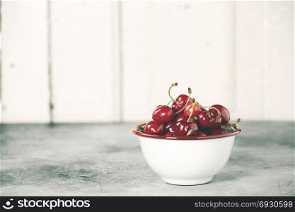 Fresh cherries in bowl on a rustick background