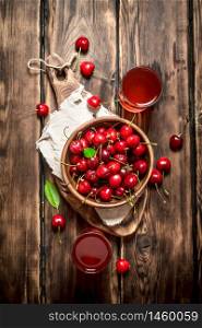 Fresh cherry and the juice in the glasses. On wooden background.. Fresh cherry and the juice in the glasses.
