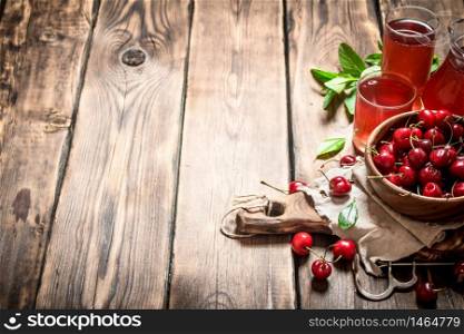 Fresh cherry and the juice in the glasses. On wooden background.. Fresh cherry and the juice in the glasses.