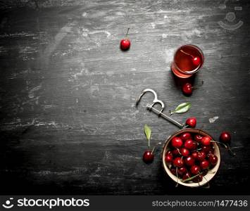 Fresh cherry in the Cup and juice in the glass. On a black wooden background.. Fresh cherries in the Cup and juice in the glass.