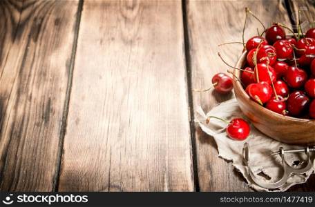 Fresh cherry in the Cup on the old fabric. On a wooden table.. Fresh cherry in the Cup on the old fabric.