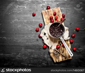 Fresh cherry jam in a saucepan on the old Board.. Fresh cherry jam in a saucepan on old Board.