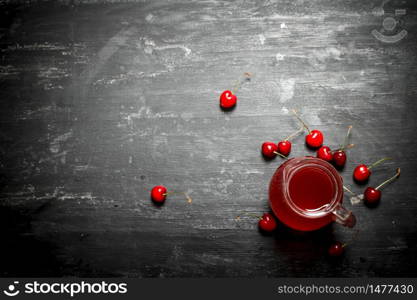 Fresh cherry juice in the pitcher. On a black wooden background.. Fresh cherry juice in the pitcher.