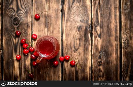 Fresh cherry juice in the pitcher. On wooden background.. Fresh cherry juice in the pitcher.