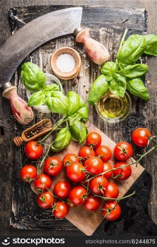 Fresh cherry tomatoes bunch with basil , salt and oil on rustic wooden background, top view. Italian food cooking ingredients.