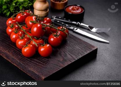 Fresh cherry tomatoes on a black background with spices. Food background. Fresh cherry tomatoes on a black background with spices