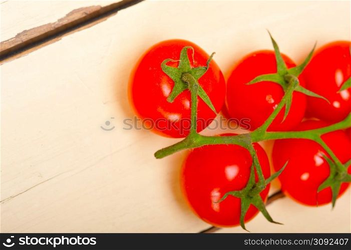 fresh cherry tomatoes on a cluster over rustic wood table