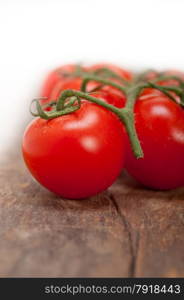 fresh cherry tomatoes on a cluster over rustic wood table