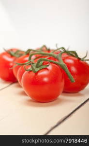 fresh cherry tomatoes on a cluster over rustic wood table