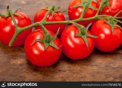 fresh cherry tomatoes on a cluster over rustic wood table