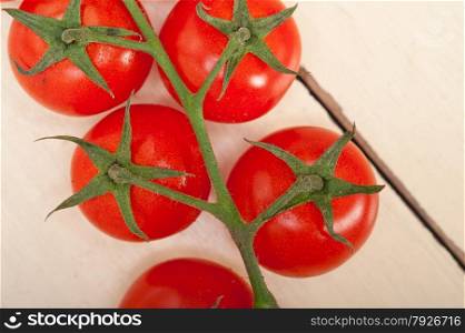 fresh cherry tomatoes on a cluster over rustic wood table
