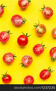 Fresh cherry tomatoes, whole and half cut isolated on yellow background. Top view