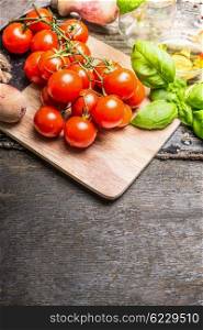 Fresh cherry tomatoes with basil and olive oil on rustic wooden background