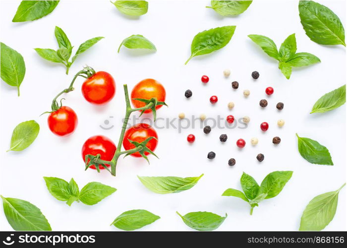 Fresh cherry tomatoes with basil leaves and different type of peppercorns on white background. Top view