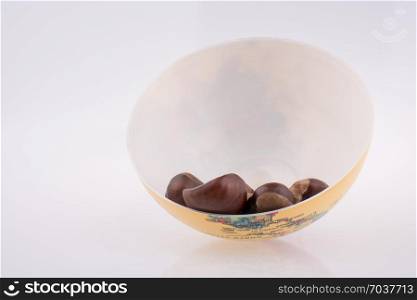 Fresh chestnuts in a bowl on a white background