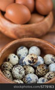 Fresh chicken eggs and quail eggs at wooden plate closeup. Fresh eggs