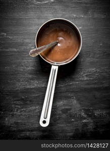 Fresh Chocolate butter in a small saucepan. On the black wooden table.. Fresh Chocolate butter in a small saucepan.