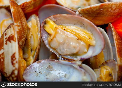 fresh clams stewed on an iron skillet over wite rustic wood table