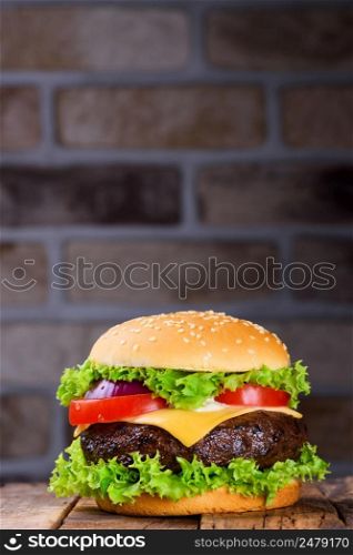 Fresh classic hamburger on rustic wooden table and brick wall on background verticall with copy space