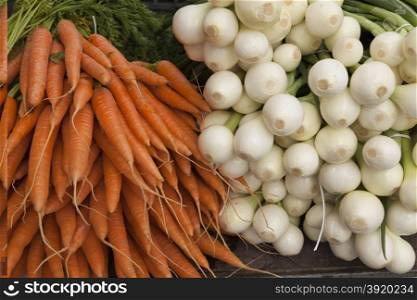 Fresh clean carrots with foliage and onion on the market. Fresh clean carrots with foliage and onion on the market.