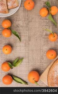 Fresh clementines and cake on wooden board with leaves. Top view with copy space.