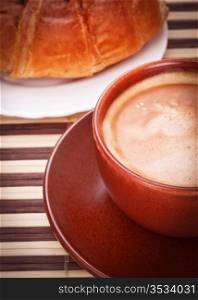 fresh coffee cup and croissant on bamboo napkin