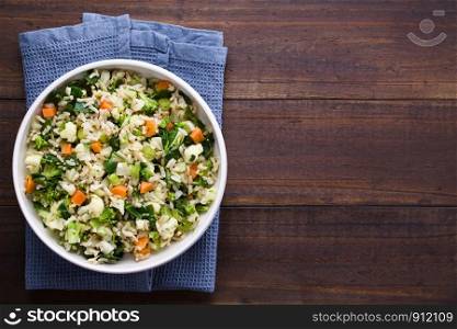 Fresh cooked brown rice with steamed vegetables (broccoli, cauliflower, swiss chard, carrot, celery) in bowl, photographed overhead with copy space on the right side . Brown Rice with Vegetables