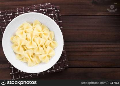 Fresh cooked farfalle, bow-tie or butterfly pasta served in bowl without sauce, photographed with copy space overhead on dark wood. Cooked Farfalle Pasta