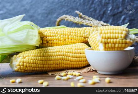 Fresh corn on cobs and sweet corn ears on rustic wooden table background - Selective focus