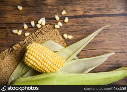 Fresh corn on sack and sweet corn seed on rustic wooden table background