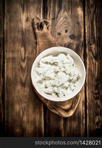 Fresh cottage cheese in a bowl . On a wooden table.. Fresh cottage cheese in a bowl .