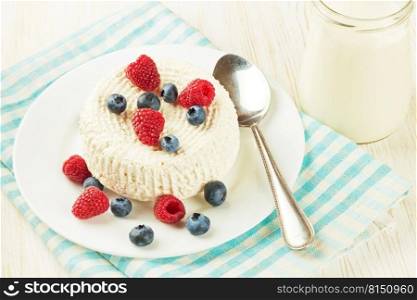 Fresh cottage cheese with raspberries and blueberries on white plate. Cottage cheese with berries on white background