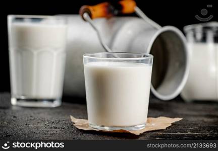 Fresh country milk in a glass on the table. On a black background. High quality photo. Fresh country milk in a glass on the table.