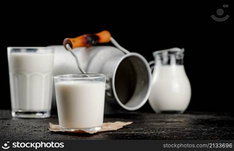 Fresh country milk in a glass on the table. On a black background. High quality photo. Fresh country milk in a glass on the table.