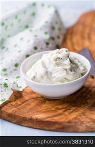Fresh cream cheese spread with herbs in a bowl, selective focus