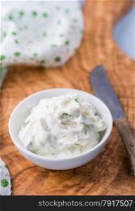 Fresh cream cheese spread with herbs in a bowl, selective focus
