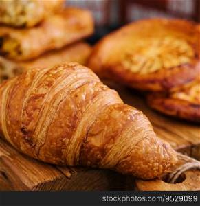 Fresh croissant and buns on wooden board