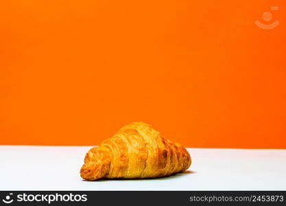 Fresh croissant isolated on orange board. French breakfast concept.. Fresh croissant isolated on orange board. French breakfast concept.