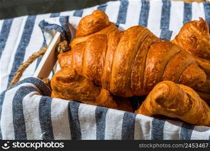 Fresh croissant, puff pastry and buttered french croissant on wooden crate. Food and breakfast concept. Detail of desserts and fresh pastries