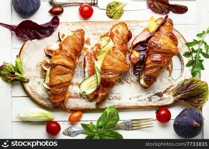 Fresh croissants with salted filling.Croissants with salmon, bacon, figs and cucumber. Croissants with meat and fish,healthy breakfast