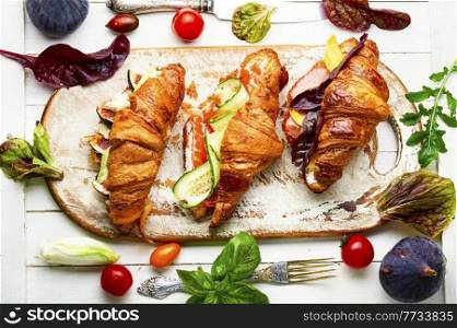 Fresh croissants with salted filling.Croissants with salmon, bacon, figs and cucumber. Croissants with meat and fish,healthy breakfast