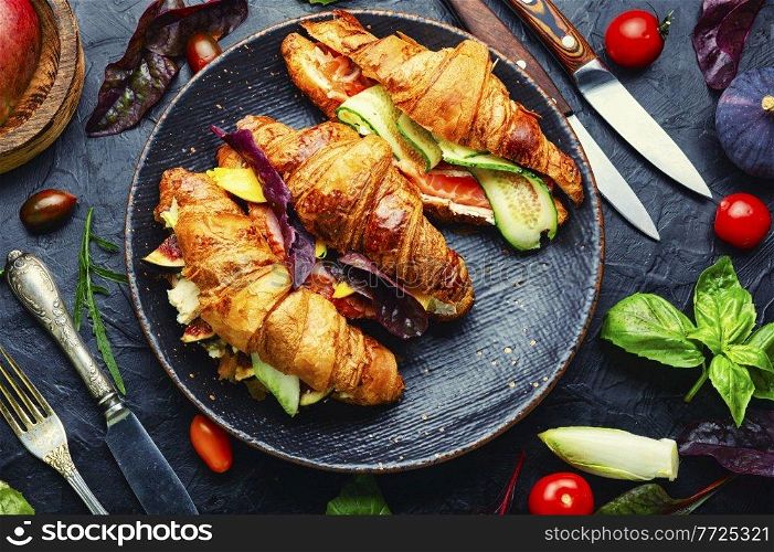 Fresh croissants with salted filling.Croissants with trout, meat bacon, vegetables and fruits. Croissant with salted filling on a plate