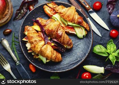 Fresh croissants with salted filling.Croissants with trout, meat bacon, vegetables and fruits. Croissant with salted filling on a plate