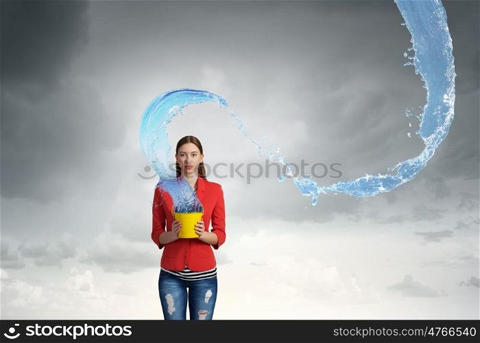 Fresh crystal water. Young woman pouring water from yellow bucket
