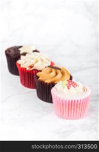 Fresh cupcake muffins with caramel and chocolate, strawberries and toffee on marble board
