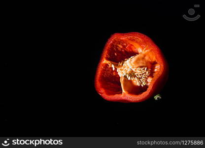 Fresh cut Bulgarian red pepper with seeds inside on a black background. cut Bulgarian red pepper with seeds inside on a black background