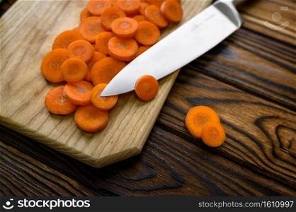 Fresh cutted carrot and knife isolated on wooden background. Organic vegetarian food, grocery assortment, natural eco products, healthy lifestyle concept. Fresh cutted carrot and knife, wooden background