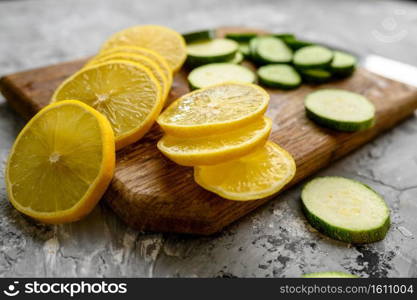 Fresh cutted lemon and cucumber on grunge abstract background. Organic vegetarian food, grocery assortment, natural eco products, healthy lifestyle concept. Cutted lemon and cucumber on grunge background