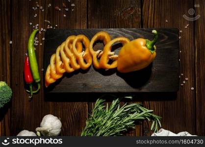 Fresh cutted pepper on board, top view, wooden background. Organic vegetarian food, grocery assortment, natural products, healthy lifestyle concept. Fresh cutted pepper on board, top view