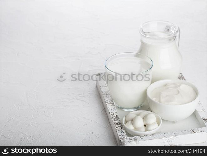 Fresh dairy products in vintage wooden box on white table background. Jar and glass of milk, bowl of sour cream and cheese.